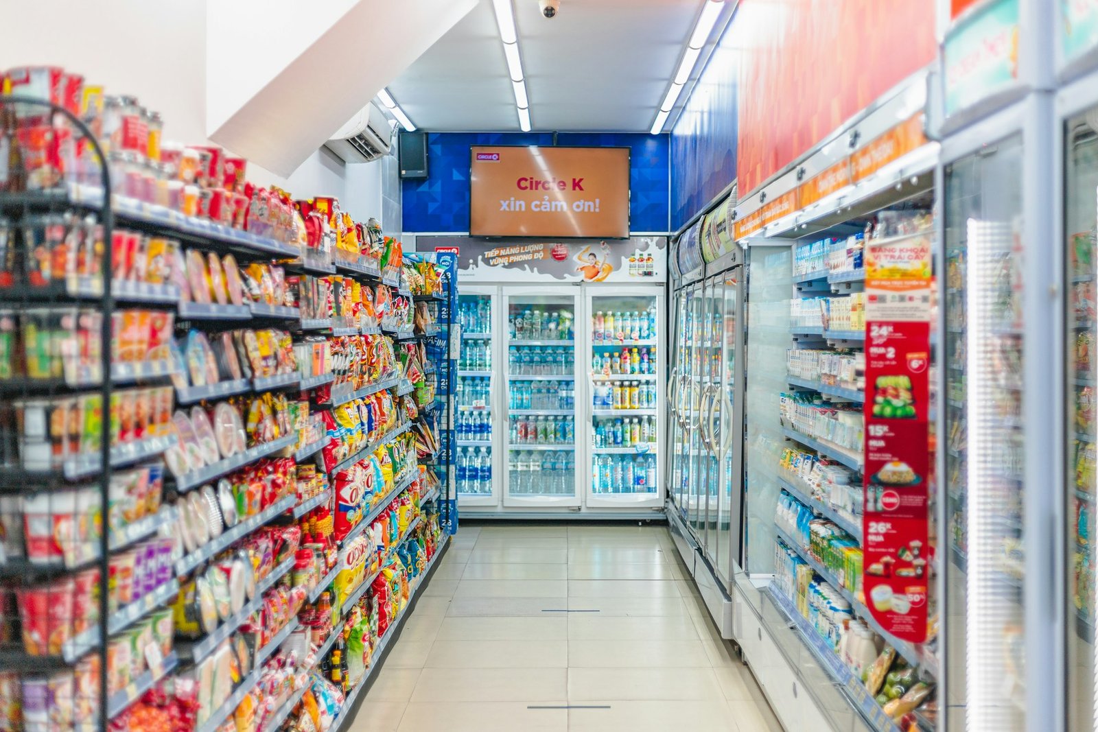 Corredor de uma loja de conveniência com snacks e geladeiras
